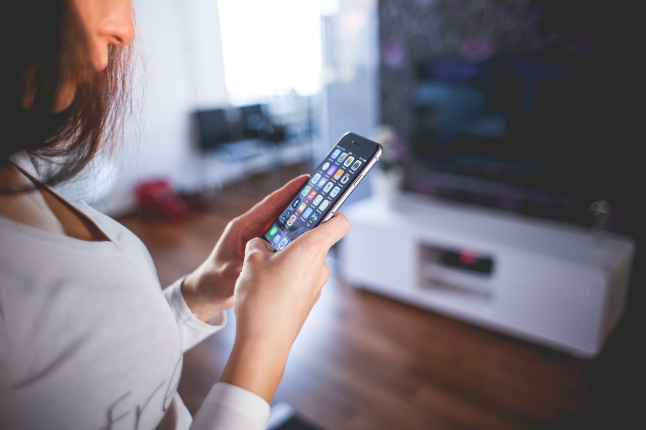 home-img Woman browsing smartphone indoors, highlighting modern technology and communication in a cozy home setting.